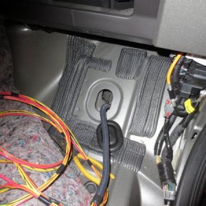 Wire routing through rubber plug on passenger side floorboard.