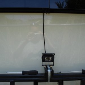 Wireless RV camera attached to back of camper (wire seen goes to 12v source in camper and to the wireless transmitter inside window.