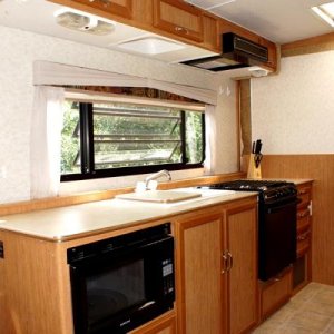 Day/night shades, ample counter space, microwave, dual sink/cover, 3 burner stove/oven, overhead vent, plenty of storage.