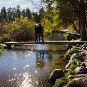 A young family standing on a walk-bridge over the Mississippi River; at it's beginning; Itasca, MN