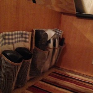 I cut a shoe pocket organizer into strips, sewed fabric along the top and attached grommets, then hung them on the side of the bed platform under the 