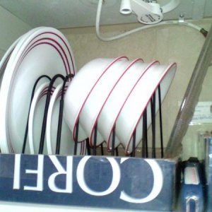 I use a wire file folder rack to store my dishes in the cabinet above the sink.  It sits in a cardboard box lid to keep it in place.