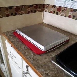 I cover the stove with a dish drying pad and a metal tray that gives me work kitchen work surface.  The pad keeps it in place while traveling.