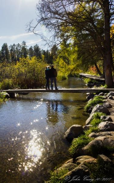 A young family standing on a walk-bridge over the Mississippi River; at it's beginning; Itasca, MN