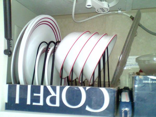 I use a wire file folder rack to store my dishes in the cabinet above the sink.  It sits in a cardboard box lid to keep it in place.