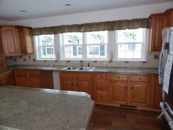 The kitchen.  In the foreground left, is a multi-level island with work/counter space on the lower side and a dining bar on the higher.