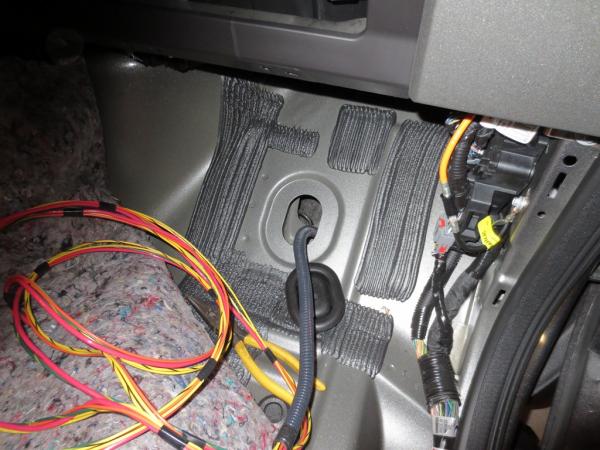 Wire routing through rubber plug on passenger side floorboard.